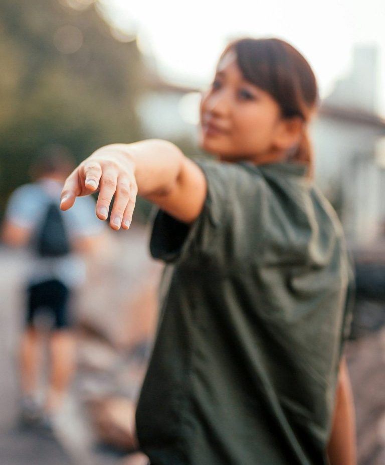 Frau in grüner Jacke, die mit ausgestrecktem Arm in die Kamera zeigt. Unschärfe im Hintergrund. Frau in grüner Jacke, die mit ausgestrecktem Arm in die Kamera zeigt. Unschärfe im Hintergrund.