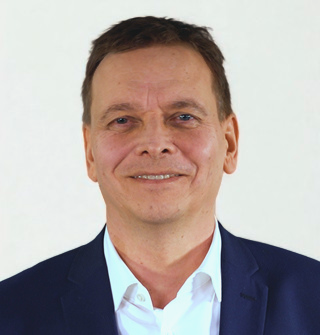 Lächelnder Mann Dr. Frank Jürgensen in Anzug vor neutralem Hintergrund. Lächelnder Mann Dr. Frank Jürgensen in Anzug vor neutralem Hintergrund.